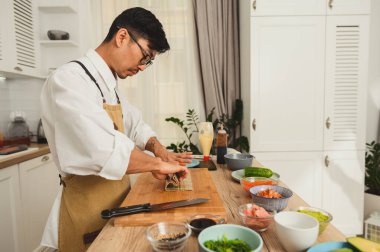 Mutfakta bambu hasırının üstünde suşi yuvarlayan bir şef. Restoranın tanıtımı.
