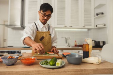 Suşi ustası mutfakta rulo hazırlıyor. Asyalı aşçının evde pişirdiği portre.