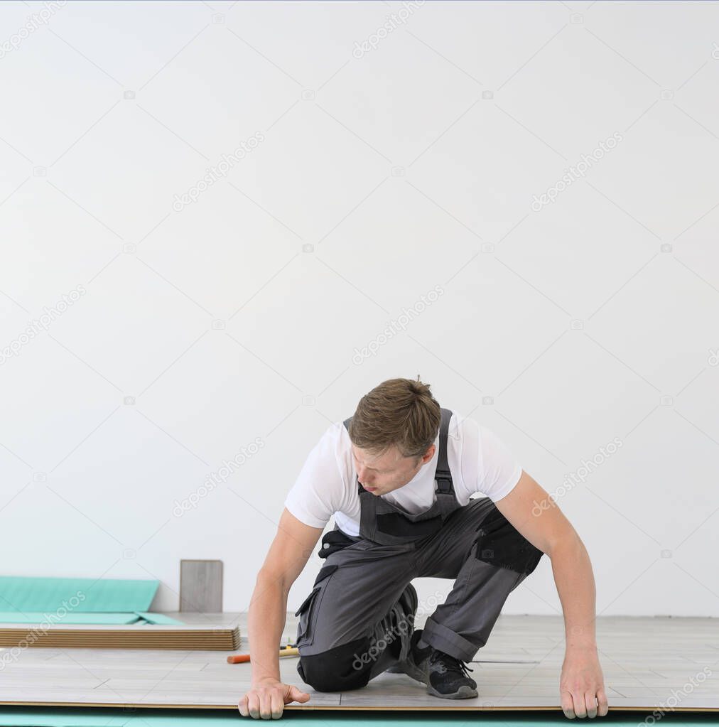 Worker in uniform lays the laminate in white room. White copy space for banner, promo
