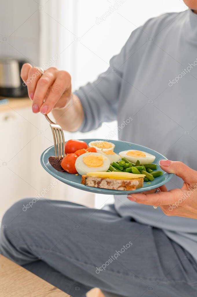 Close up woman holds Healthy Breakfast of boiled eggs and steamed vegetables on plate, balanced breakfast concept.