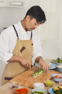 Asyalı şef üniforması taze suşi dilimliyor. İnternetten yemek servisi. Japon mutfağı: ekmek, soya sosu, wasabi. Restoran afişi
