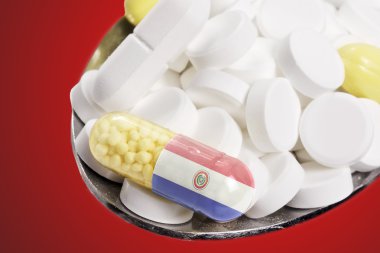 Spoon full of pills and a capsule with the flagdesign of Paragua