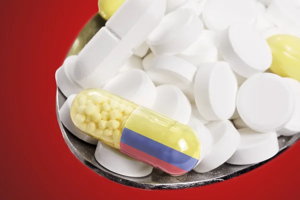 Spoon full of pills and a capsule with the flagdesign of Colombi — Stockfoto