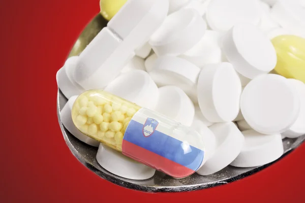 Spoon full of pills and a capsule with the flagdesign of Sloveni — стокове фото