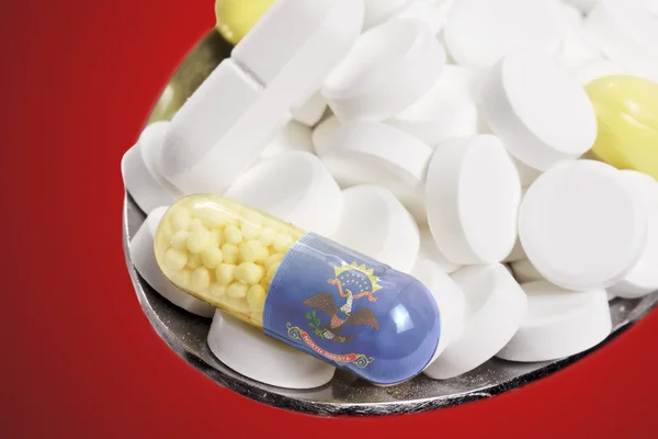 Spoon full of pills and a capsule with the flagdesign of North D — Stockfoto