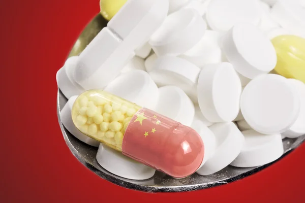 Spoon full of pills and a capsule with the flagdesign of China.( — Stockfoto