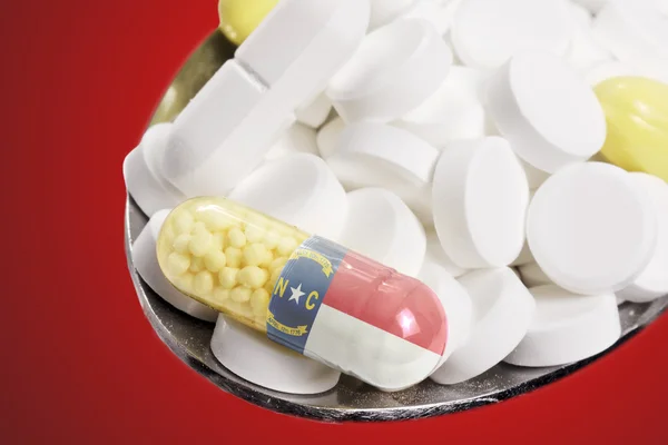 Spoon full of pills and a capsule with the flagdesign of North C — Stockfoto