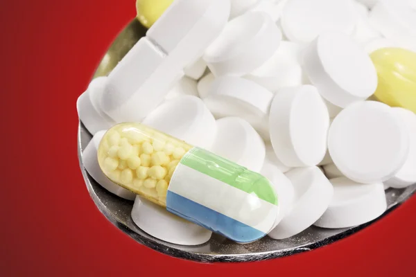 Colher cheia de comprimidos e uma cápsula com o flagdesign de Sierra — Fotografia de Stock