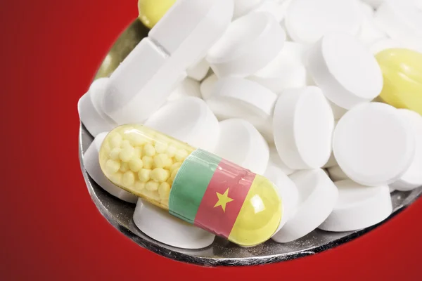 Spoon full of pills and a capsule with the flagdesign of Cameroo — 图库照片