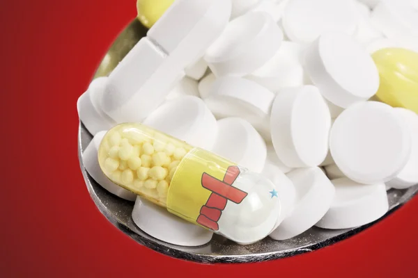 Spoon full of pills and a capsule with the flagdesign of Nunavut — Stockfoto