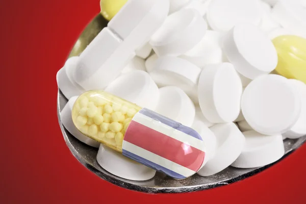 Spoon full of pills and a capsule with the flagdesign of Costa R — Stockfoto