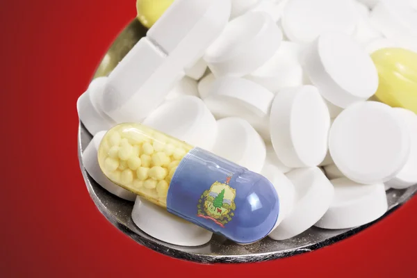 Spoon full of pills and a capsule with the flagdesign of Vermont — Stockfoto