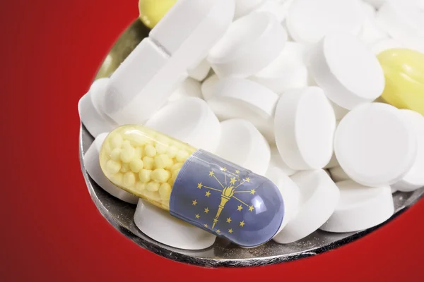 Colher cheia de pílulas e uma cápsula com o flagdesign de Indiana — Fotografia de Stock