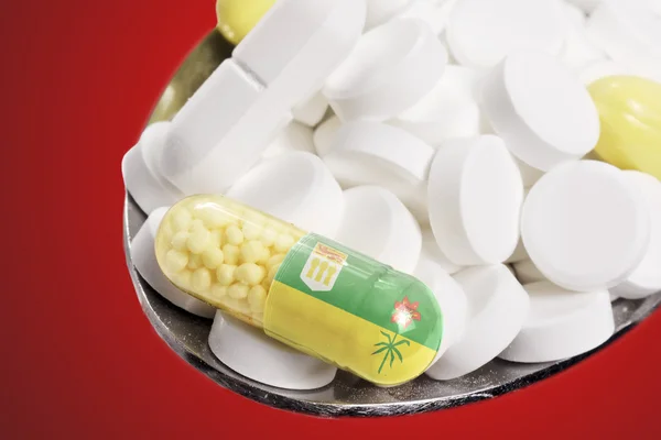 Spoon full of pills and a capsule with the flagdesign of Saskatc 图库图片