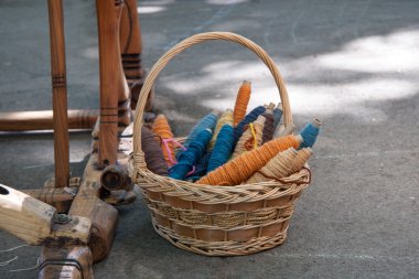 Eski bir tezgâh altında bir sepet içinde ev yapımı yün iplik