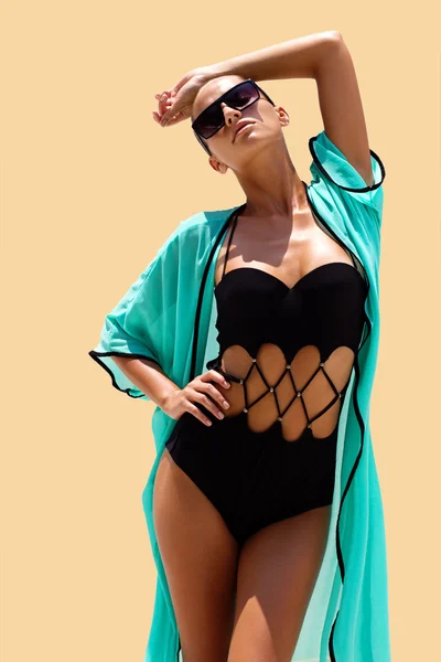 Femme dansante en maillot de bain noir lunettes de soleil et robe de plage turquoise pose sur fond de couleur. Un look mode. Cheveux levés. Tan girl — Photo