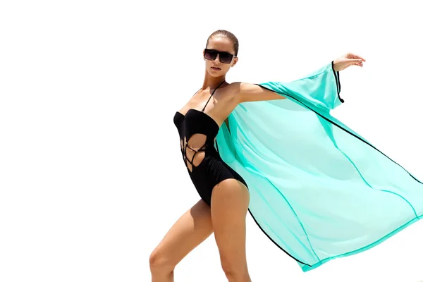 Γυναίκα που χορεύει σε γυαλιά ηλίου μαύρο μαγιό και παραλία τυρκουάζ φόρεμα θέτει σε λευκό φόντο σε απομόνωση. Εμφάνιση της μόδας. Μαλλιά επάνω. Κορίτσι μαύρισμα — Φωτογραφία Αρχείου