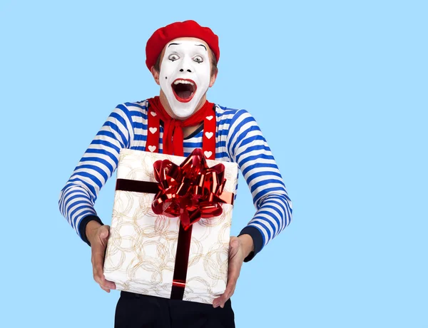 Mime with present.Emotional смішний актор в костюмі моряка, червоний берет позує на синьому фоні . — стокове фото