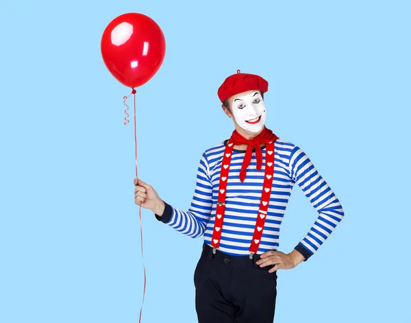 Mime with balloon.Emotional funny actor wearing sailor suit, red beret posing on blue background. — Stockfoto