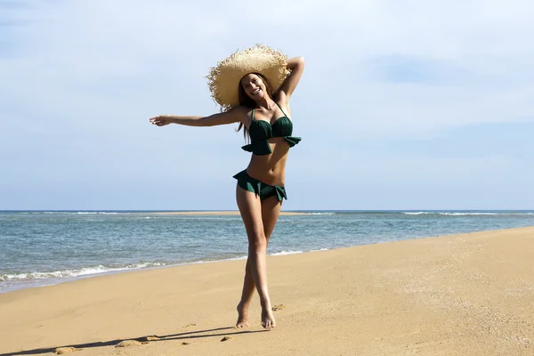 Femme en chapeau sur la plage. Belle fille souriante portant des poses de bikini vert marchant près de la mer. Look de mode . — Photo