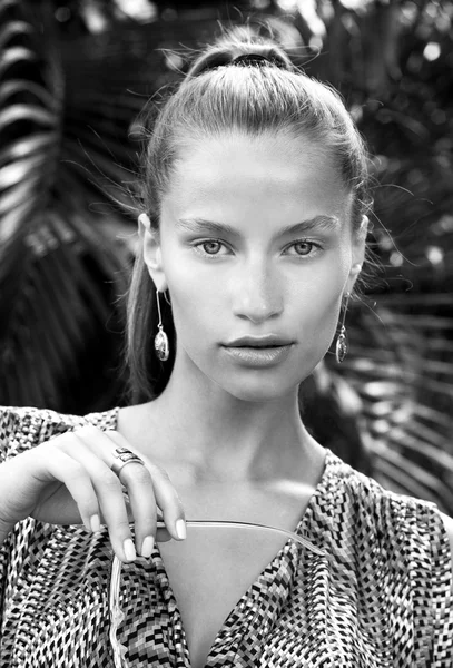 Retrato de mulher de moda bonita em trópicos com óculos de sol pretos. Menina sexy vestindo macacões de cor, brincos elegantes e poses de anel na ilha . — Fotografia de Stock