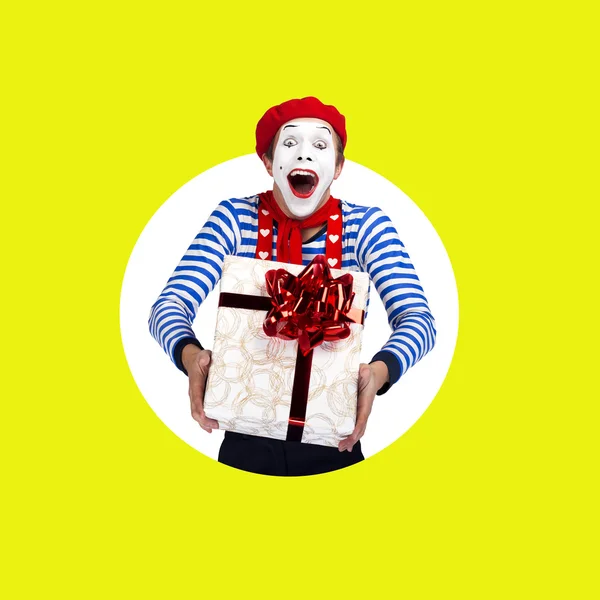Überraschte Pantomime mit Geschenk. Lustiger Schauspieler in roter Baskenmütze, Matrosenanzug posiert auf farbigem Hintergrund — Stockfoto