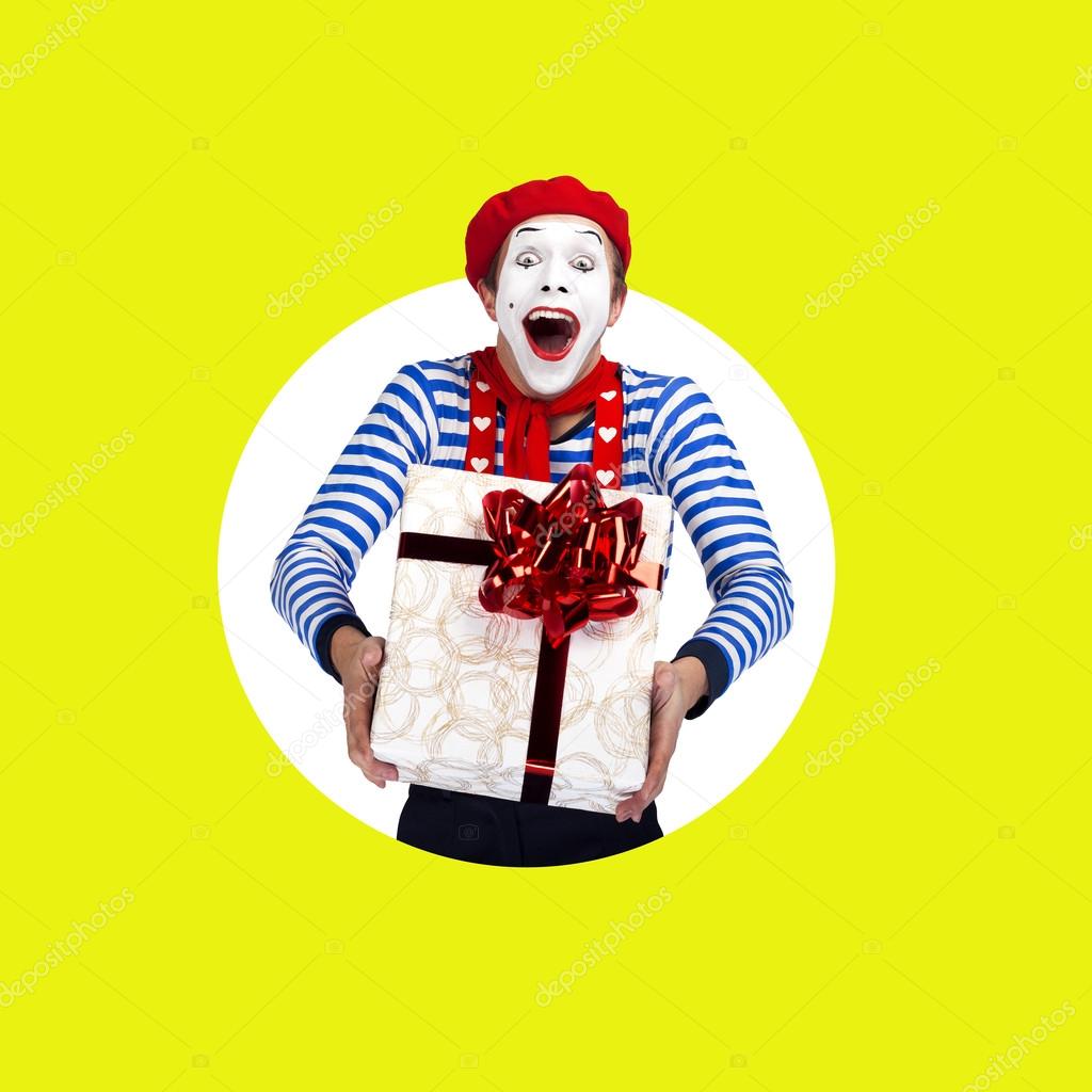 Surprised mime with gift.Funny actor in red beret, sailor suit poses on color background