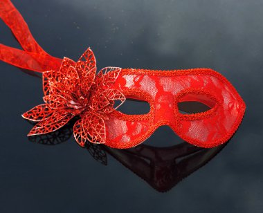 Siyah masanın üzerinde yatan kırmızı karnaval maskeli balo maskesi.