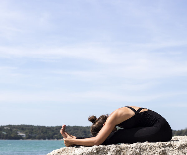 Yoga woman poses on beach near sea and rocks. Phuket island, Thailand