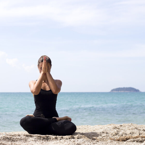 Yoga woman poses on beach near sea and rocks. Phuket island, Thailand