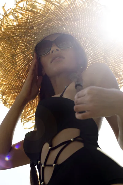 Femme en lunettes de soleil et chapeau noir élégant maillot de bain avec des nattes pose sur le toit bénéficiant d'une vue sur le paysage. Île de Phuket, Thaïlande. Look haute couture . — Photo
