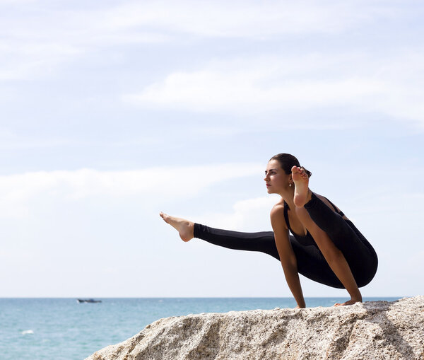 Yoga woman poses on beach near sea and rocks. Phuket island, Thailand