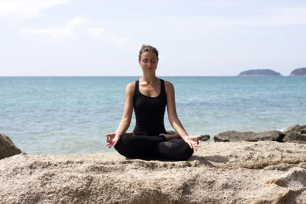 Mulher de ioga posa na praia perto do mar e pedras. Phuket Island, Tailândia — Fotografia de Stock