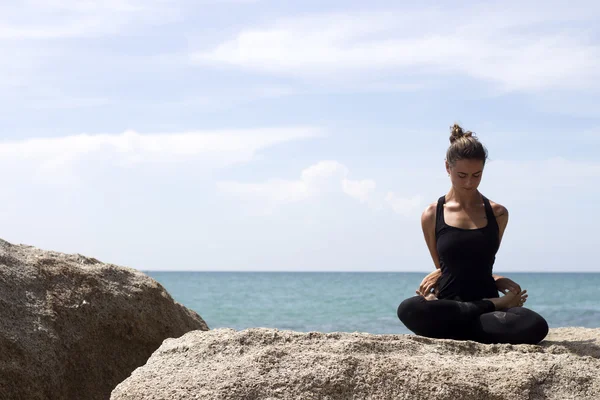Donna di yoga posa sulla spiaggia vicino al mare e rocce. Isola di Phuket, Thailandia — Foto Stock