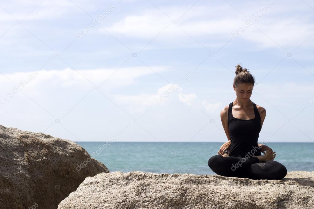 Yoga woman poses on beach near sea and rocks. Phuket island, Thailand