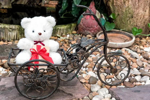 Ursinho de pelúcia branco segurando presente na bicicleta — Fotografia de Stock