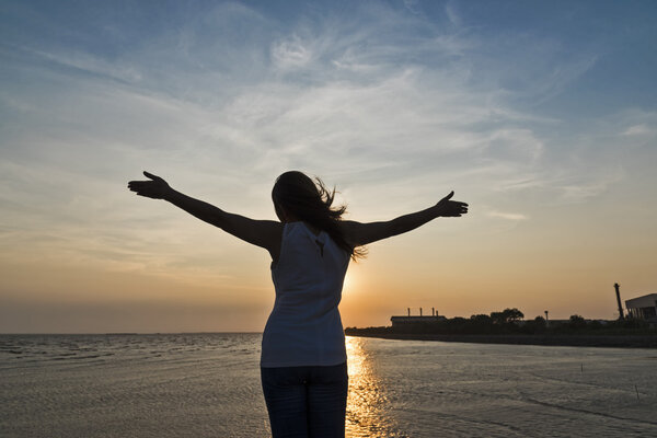young cheering woman open arms at sunset 