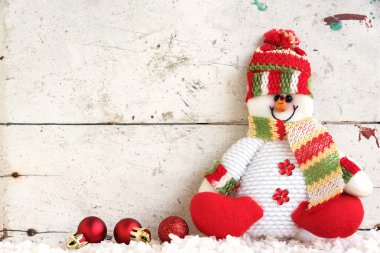 Noel topu ile kar üzerinde oturan kardan adam