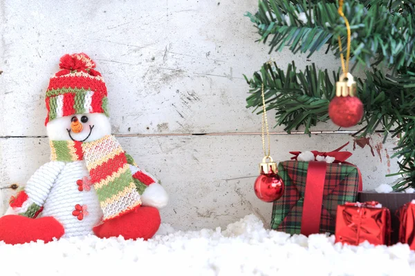 Boneco de neve sentado na neve com árvore de natal — Fotografia de Stock