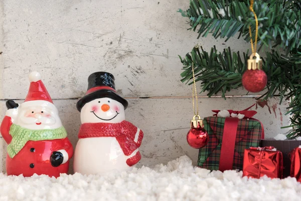 Santa claus y muñeco de nieve en la nieve con árbol de Navidad en el fondo vintage —  Fotos de Stock