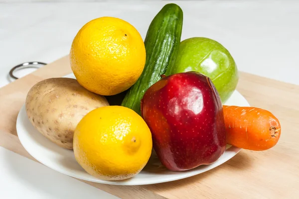 Piatto di frutta e verdura sul tagliere Fotografia Stock