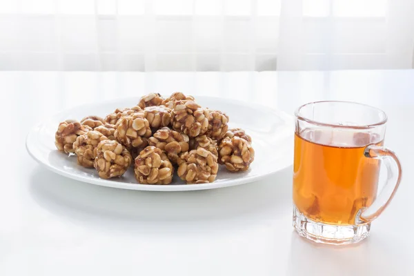 Sweet peanut balls in a plate and glass of black tea