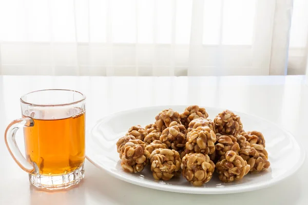 Sweet peanut balls in a plate and glass of black tea