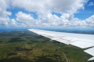 Bulutların üzerinde tropikal ada üzerinde uçan bir uçağın kanat