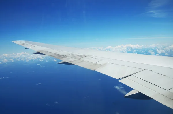 Szárny egy repülőgép repül a felhők felett trópusi sziget — Stock Fotó