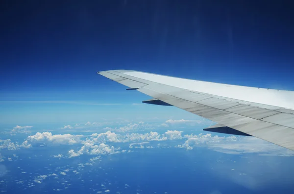Ala de un avión volando por encima de las nubes sobre la isla tropical —  Fotos de Stock