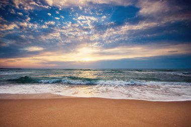 Sahilde güneşin doğuşu ve dramatik bulutlar.