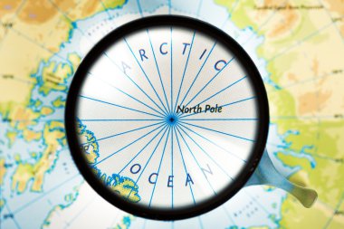 Map, magnifying glass and Arctic ocean on the focus clipart