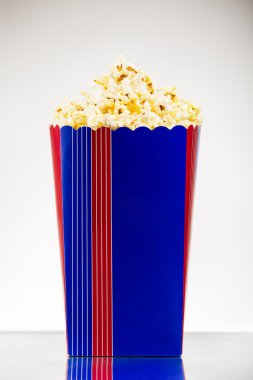 Beyaz arka planda çizgili kovada patlamış mısır