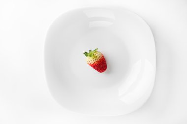 Taze organik çilek beyaz izole bir porselen tabak içinde